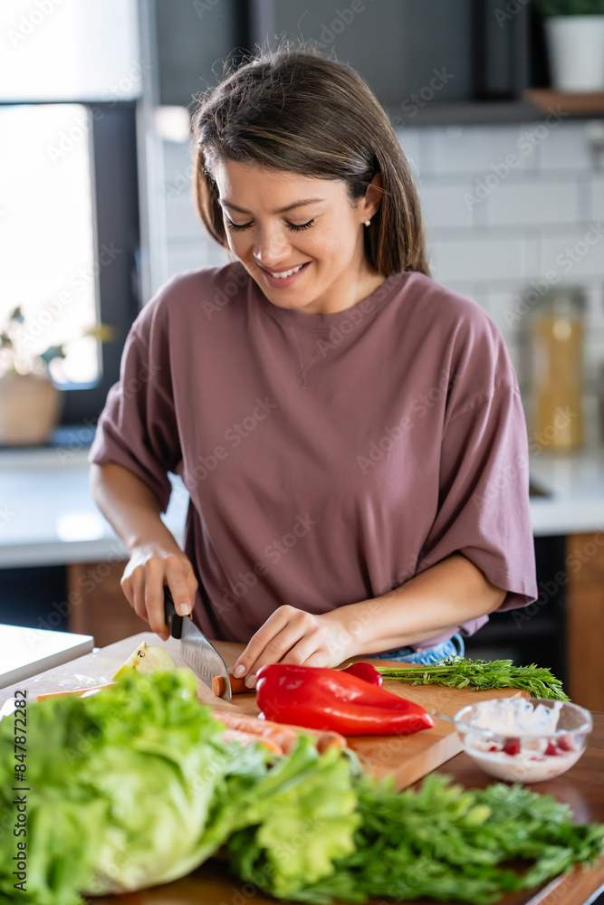 A young pretty cheerful woman is preparing a healthy various vegetable-based meal at home A young pretty cheerful woman is preparing a healthy various vegetable-based meal at home