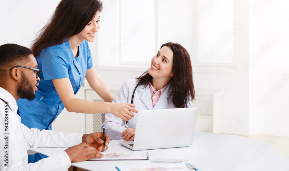 Team Of Practitioners Examining Medical Reports On Laptop, Having Meeting At Hospital Team Of Practitioners Examining Medical Reports On Laptop, Having Meeting At Hospital