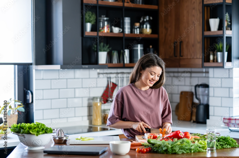 A young pretty cheerful woman is preparing a healthy various vegetable-based meal at home A young pretty cheerful woman is preparing a healthy various vegetable-based meal at home