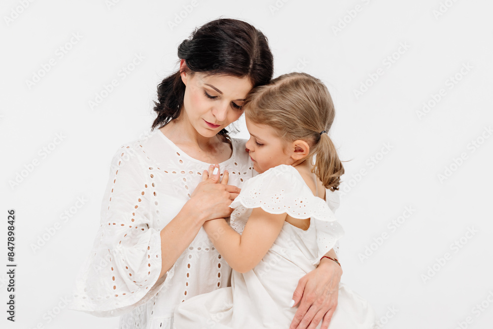 Family relationships between mother and daughter. Sensual mother with her little daughter on a light studio background. Tender moment, family support. Family relationships between mother and daughter. Sensual mother with her little daughter on a light studio background. Tender moment, family support.