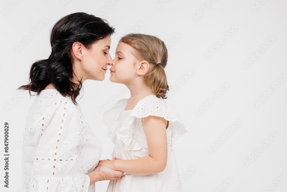 Close-up of a touching and gentle mother and daughter on a light background. Mom's tender touch. Family concept. Close-up of a touching and gentle mother and daughter on a light background. Mom's tender touch. Family concept.