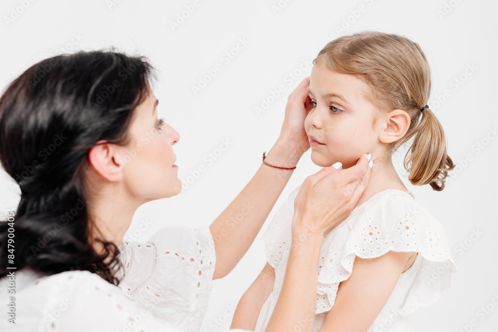 Close-up of a touching and gentle mother and daughter on a light background. Mom's tender touch. Family concept. Close-up of a touching and gentle mother and daughter on a light background. Mom's tender touch. Family concept.