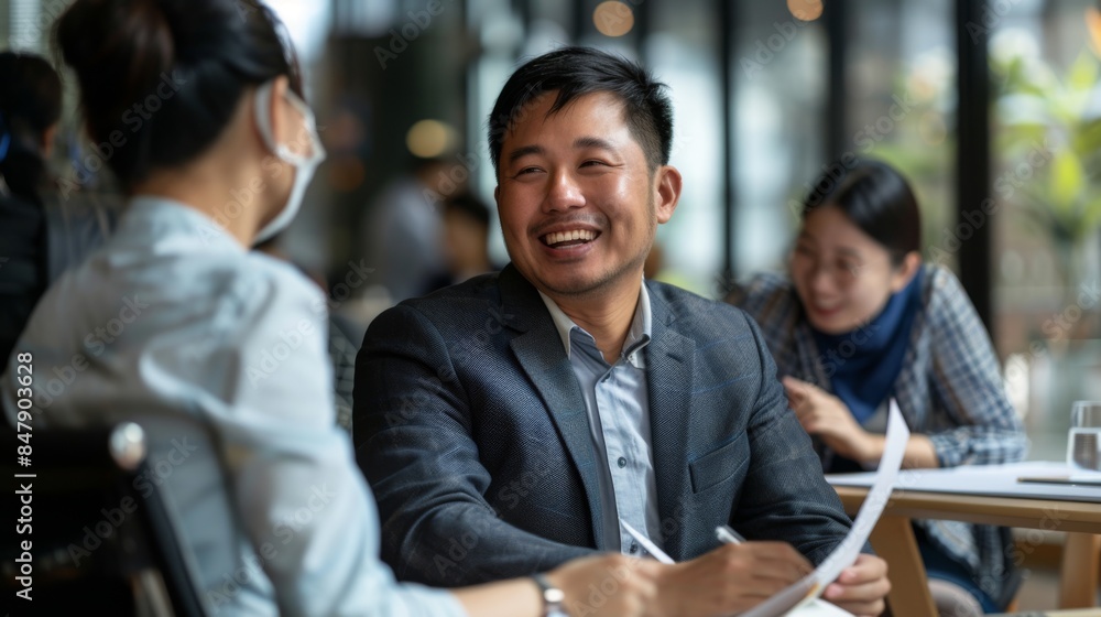 A man in a suit smiles while reviewing documents with colleagues at a cafe A man in a suit smiles while reviewing documents with colleagues at a cafe