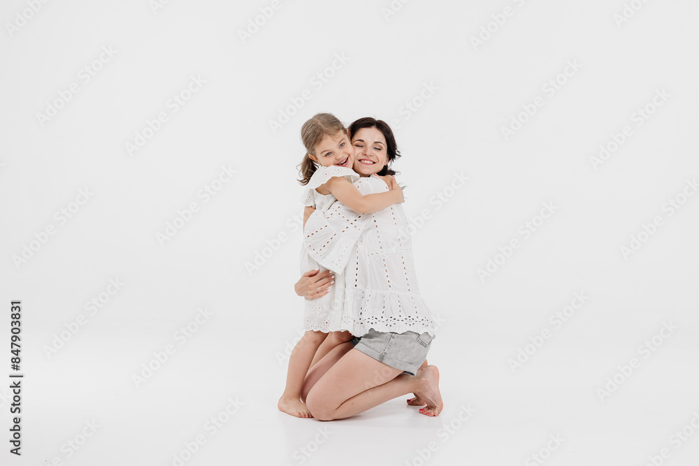 Happy mother and daughter playing and having fun on a white background. Concept of a happy family, motherhood, style and fashion. Happy mother and daughter playing and having fun on a white background. Concept of a happy family, motherhood, style and fashion.