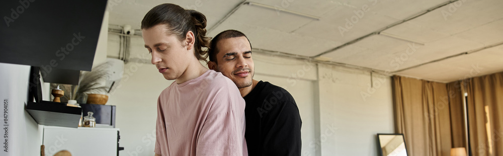 A young gay couple shares a tender moment in their modern home, their connection evident in their embrace. A young gay couple shares a tender moment in their modern home, their connection evident in their embrace.