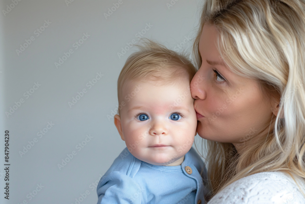 Mother kissing her baby on the cheek in tender moment, love and care concept Mother kissing her baby on the cheek in tender moment, love and care concept