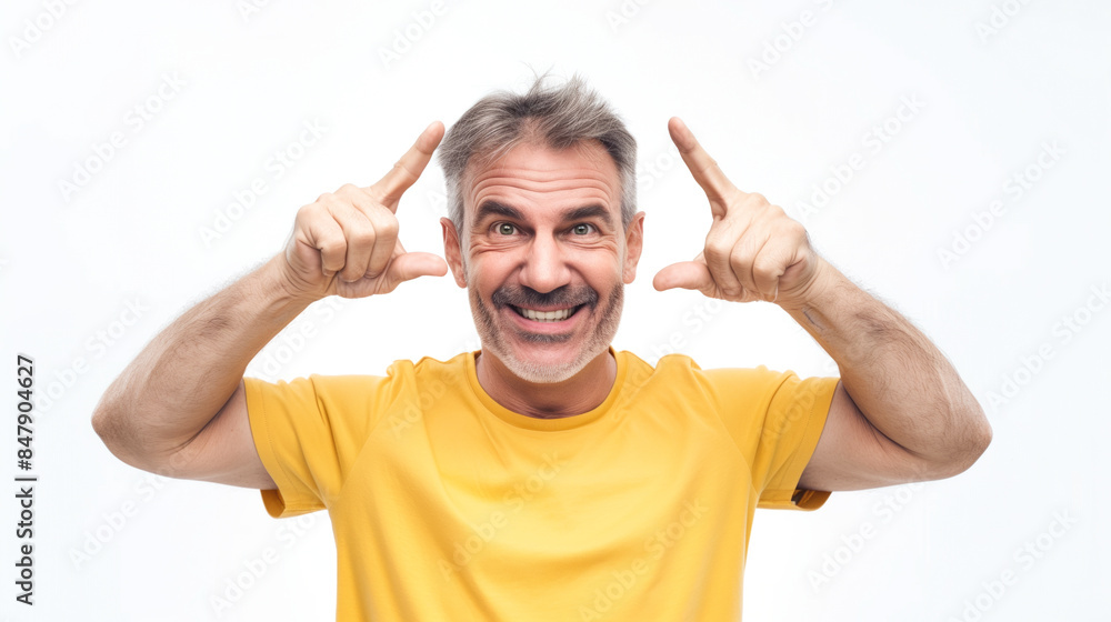 Smiling mature man in a yellow shirt, pointing at his temples with both index fingers Smiling mature man in a yellow shirt, pointing at his temples with both index fingers