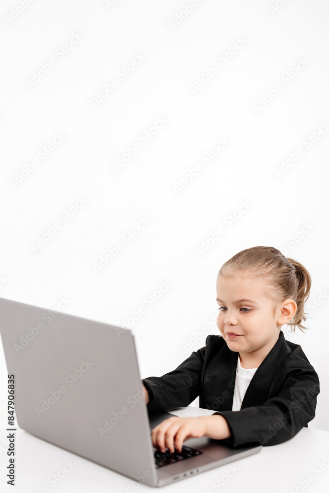 Little business girl child working or studying on a light background with a laptop. Modern online education, business and technology. Little business girl child working or studying on a light background with a laptop. Modern online education, business and technology.