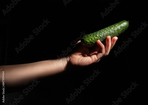 cucumber in hand on black background