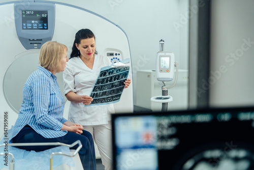 Foto A woman is sitting in a hospital room with a doctor looking at a medical image