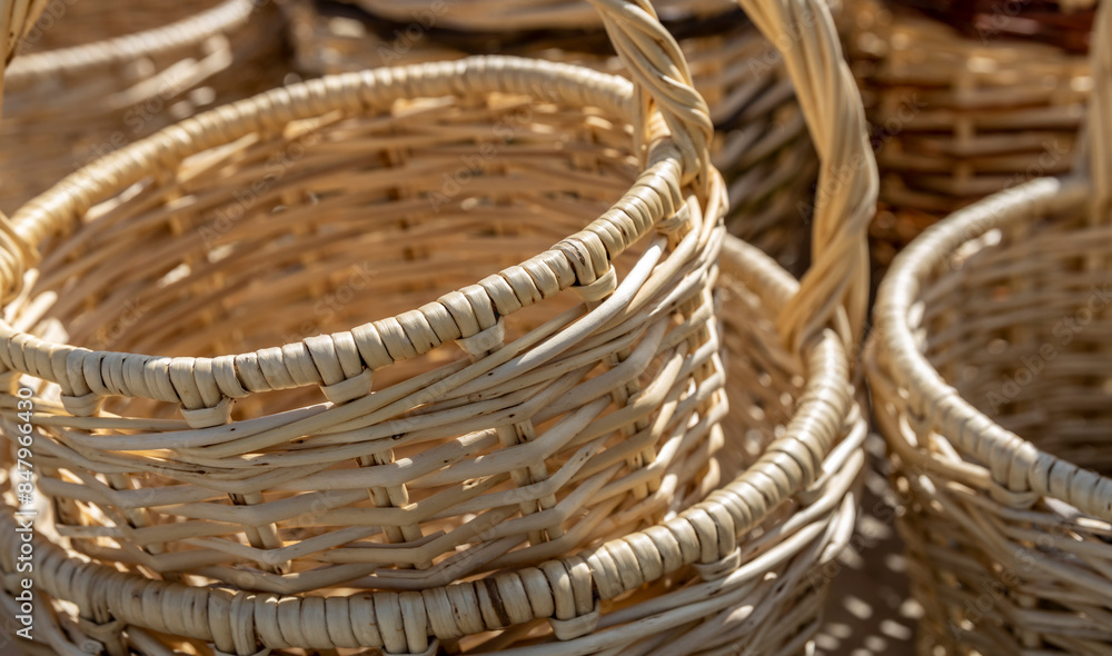 A close-up image of multiple woven baskets stacked together, bathed in warm sunlight. The natural materials and intricate craftsmanship create a sense of rustic charm.