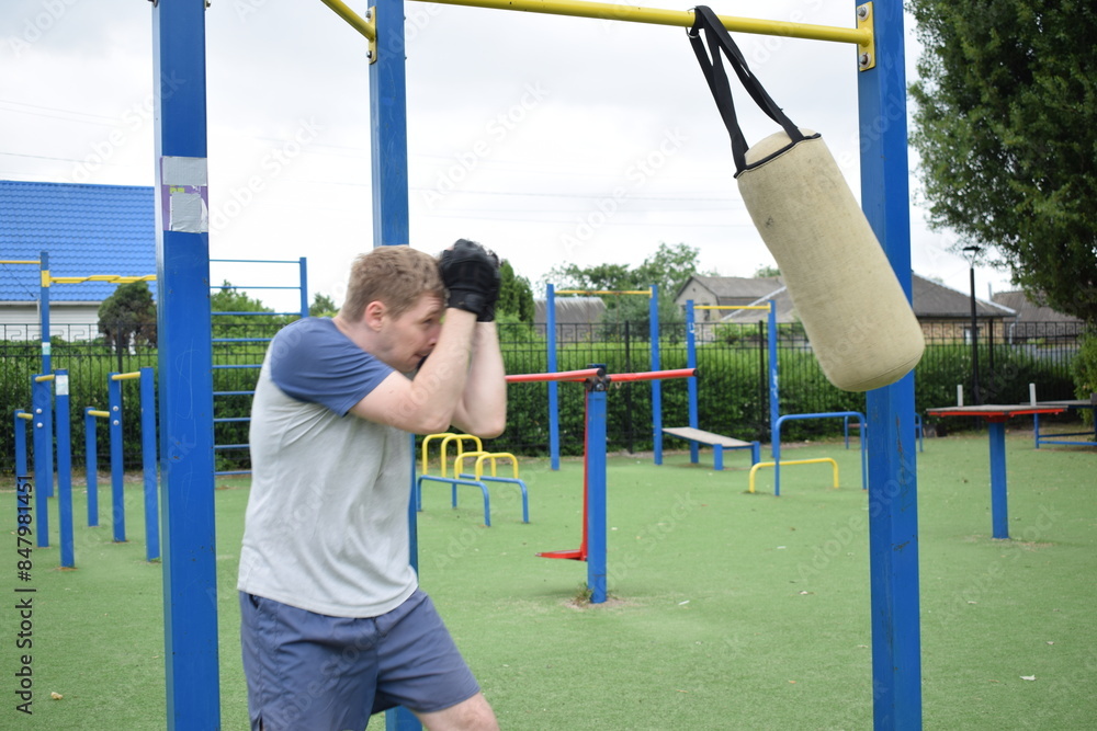 Obraz premium A young man in sportswear engages in a workout, using a sport tool for physical exercises on a sports field in the morning. His dedication to fitness performs training routine with focus and energy