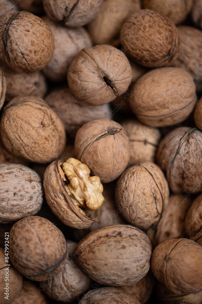 Walnuts in shell. One cracked nut on them. pile of nuts. frame is filled with nuts. Nut texture. Close-up. Top view. High quality photo Walnuts in shell. One cracked nut on them. pile of nuts. frame is filled with nuts. Nut texture. Close-up. Top view. High quality photo
