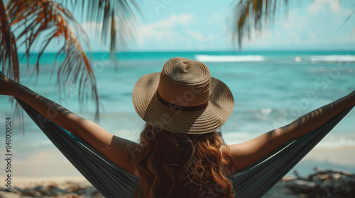 Woman in a sun hat relaxing on a hammock by the seaside, conveys peace and serenity