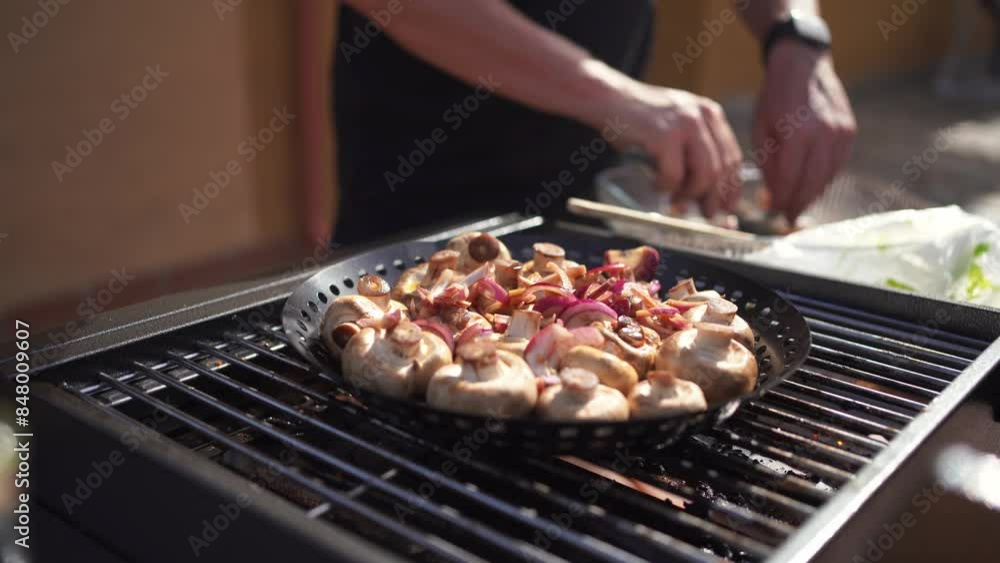 Mushrooms being grilled on a barbecue grill, with a person's hand in the background preparing the food Mushrooms being grilled on a barbecue grill, with a person's hand in the background preparing the food