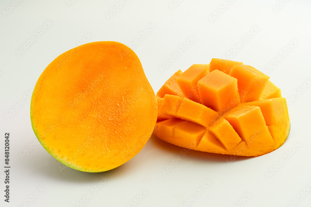 mango cut in half vertically next to mango cut lying down with rectangular cuts on a white background mango cut in half vertically next to mango cut lying down with rectangular cuts on a white background
