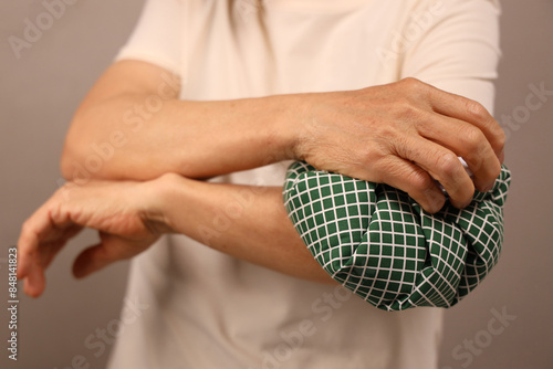 Tableau sur toile An elderly person applying a cold compress to his elbow with an ice pack due to elbow pain