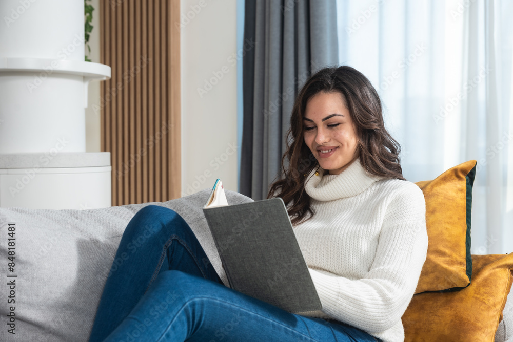 Young happy freshly divorced or recently single woman after toxic relationship breakup sitting alone at home on sofa writing diary and notes about her negative experience after she recover from stress Young happy freshly divorced or recently single woman after toxic relationship breakup sitting alone at home on sofa writing diary and notes about her negative experience after she recover from stress