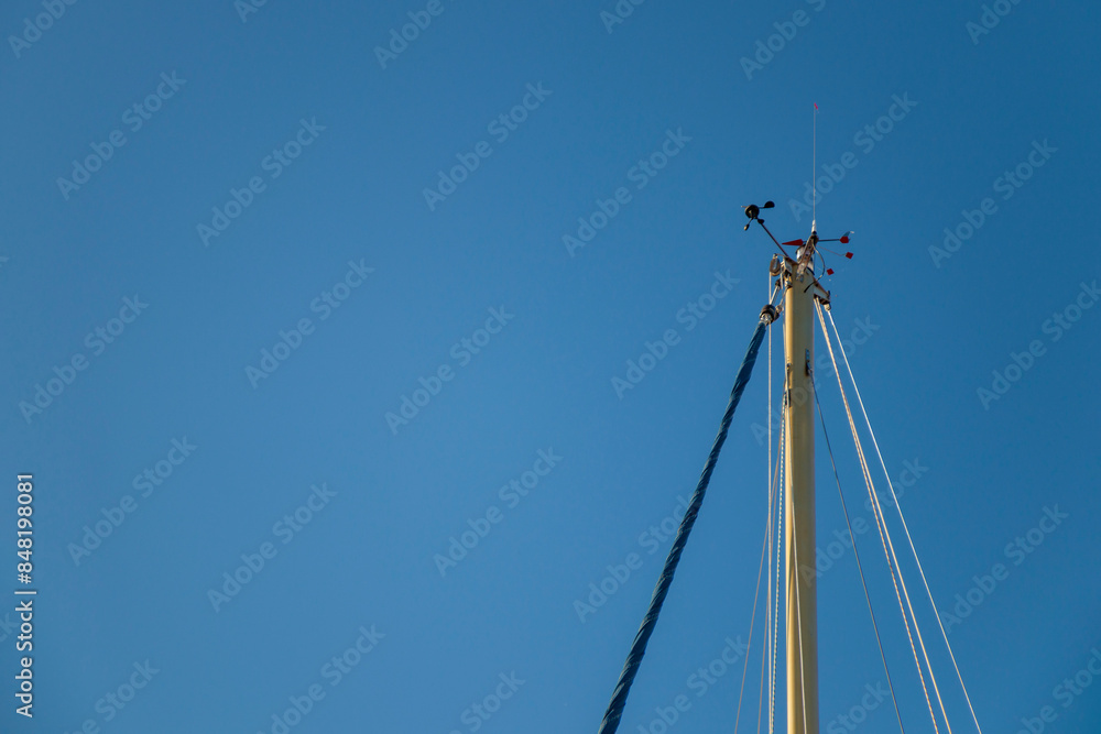 Wind indicator mounted on top of a sailboat mast. Wind direction and speed on a sailboat and blue sky Wind indicator mounted on top of a sailboat mast. Wind direction and speed on a sailboat and blue sky
