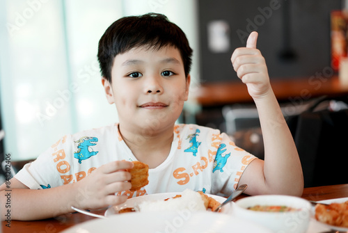 Cute asian boy eating Chicken Nugget by self. Background. Copy space.	