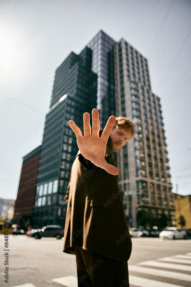 A red-haired man in dapper attire raising his hand energetically. A red-haired man in dapper attire raising his hand energetically.