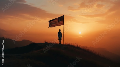 A man stands on a hill holding a American flag