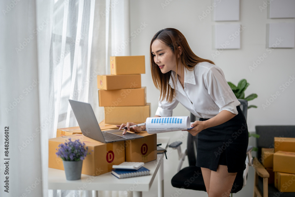 A woman is sitting at a desk with a laptop and a stack of boxes in front of her A woman is sitting at a desk with a laptop and a stack of boxes in front of her