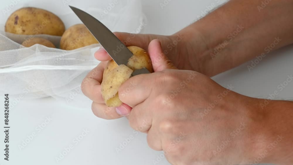 A man peels potatoes on a white background, close-up. Cooking food. A man peels potatoes on a white background, close-up. Cooking food.