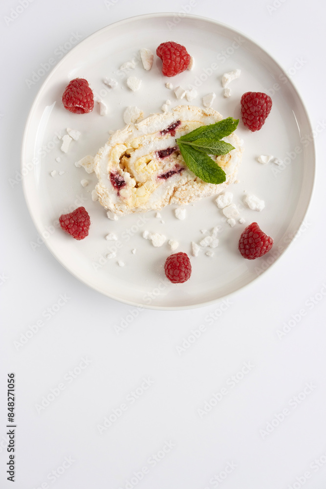 Raspberry meringue roll on a white plate close-up. Dessert on a white background. Breakfast decorated with berries Raspberry meringue roll on a white plate close-up. Dessert on a white background. Breakfast decorated with berries