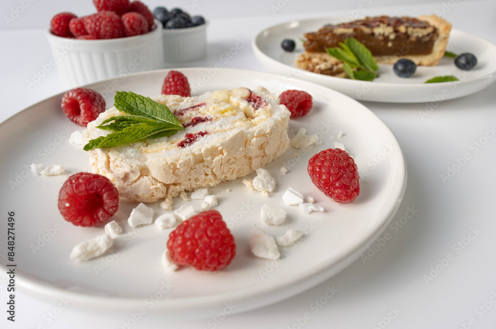 Raspberry meringue roll on a white plate close-up. Dessert on a white background. Breakfast decorated with berries Raspberry meringue roll on a white plate close-up. Dessert on a white background. Breakfast decorated with berries
