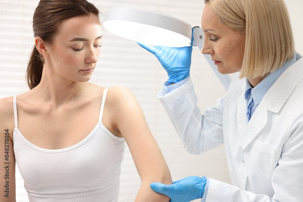 Dermatologist examining patient under lamp in clinic Dermatologist examining patient under lamp in clinic