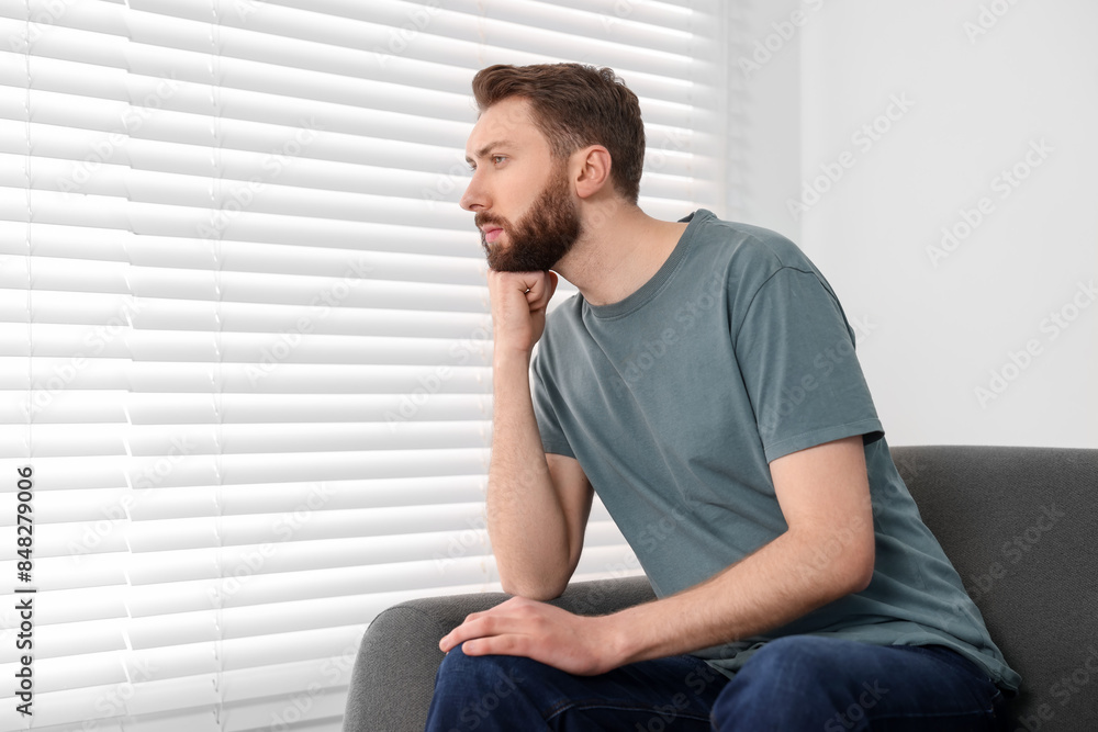 Loneliness concept. Sad man sitting on sofa at home, space for text Loneliness concept. Sad man sitting on sofa at home, space for text