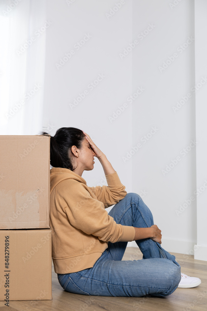 Young woman takes a break while packing her things into boxes to move into her new house. Woman overwhelmed by the move. She is a homeowner, mortgage concept. New home, new life Young woman takes a break while packing her things into boxes to move into her new house. Woman overwhelmed by the move. She is a homeowner, mortgage concept. New home, new life