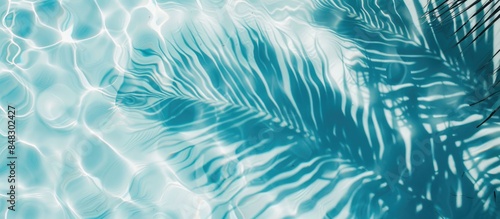 Top view of a palm leaf shadow cast on a serene blue water background in a flat lay perspective.