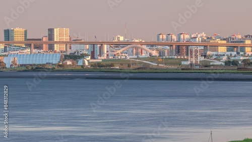 Park Tejo and river timelapse in Lisbon with park of Nations district modern architecture on a background, Portugal. View with Vasco da Gama Bridge from walking route Percurso Ribeirinho de Loures photo