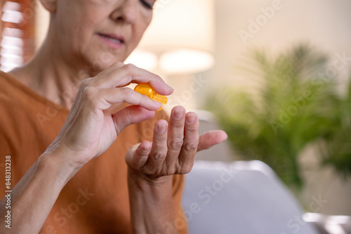 Elderly Woman Taking Care of Her Health by Applying Medication at Home, Senior Health and Wellness, Self-Care Routine, Healthy Aging, Close-Up of Hands, Daily Health Maintenance photo