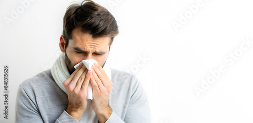 Man wiping his nose with a handkerchief after sneezing, the concept of a cold or allergic disease, on white backround, copyspace