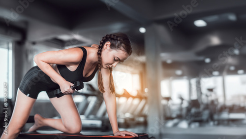 Cinematic tone of young attractive fitness woman exercise with dumbbell in gym. Individual sport to fit muscles of body for healthy life concept. © totojang1977