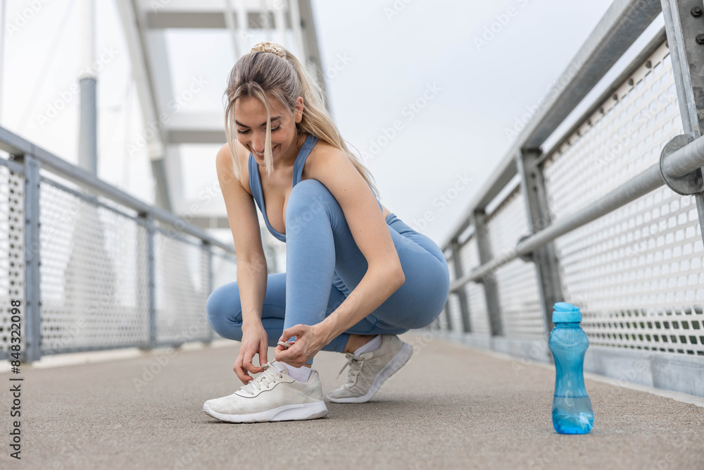 On the bridge, a moment is taken by a young woman to meticulously tie her shoelace, ensuring her footing is secure for the journey ahead, a blend of preparation and mindfulness in her stride On the bridge, a moment is taken by a young woman to meticulously tie her shoelace, ensuring her footing is secure for the journey ahead, a blend of preparation and mindfulness in her stride