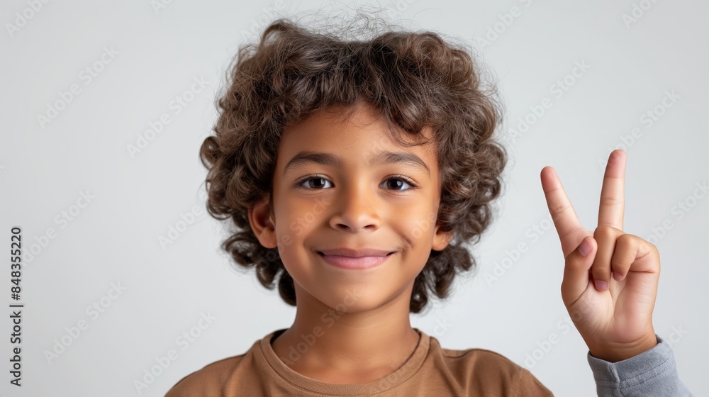 A young boy with a bright smile flashes a peace sign, capturing the essence of joy and innocence. A young boy with a bright smile flashes a peace sign, capturing the essence of joy and innocence.