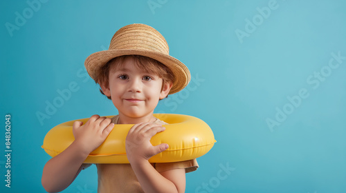 Menino bonitinho com chapéu panamá e braçadeiras infláveis ​​em fundo azul photo