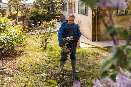 Middle-aged man tending to garden in sunny backyard