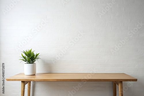 Minimalist wooden table with a small potted plant against a white brick wall