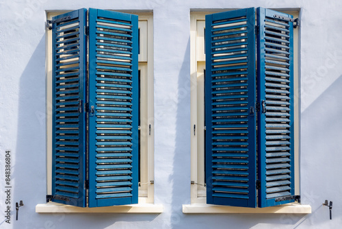 Foto Half opened vintage blue colour window in summer with white cement, Wooden louver window with concrete wall with sunlight, Louvered shutters and shading with horizontal blades, Abstract background