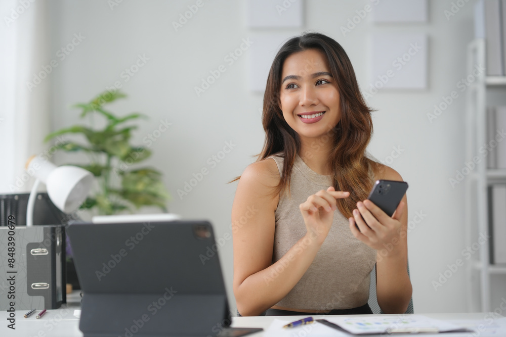 Smiling woman working at desk with tablet and smartphone, business setting with plants and organized workspace, modern office environment. Smiling woman working at desk with tablet and smartphone, business setting with plants and organized workspace, modern office environment.