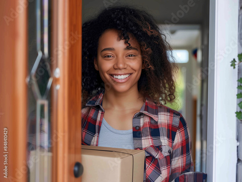A woman with curly hair is smiling and holding a box