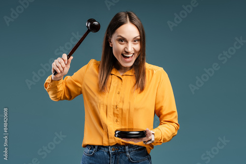 Portrait of a happy young woman knocking a gavel in the studio, looking at camera photo