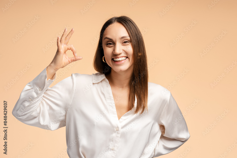 Happy pretty young woman in white shirt showing ok symbol with finger, isolated Happy pretty young woman in white shirt showing ok symbol with finger, isolated