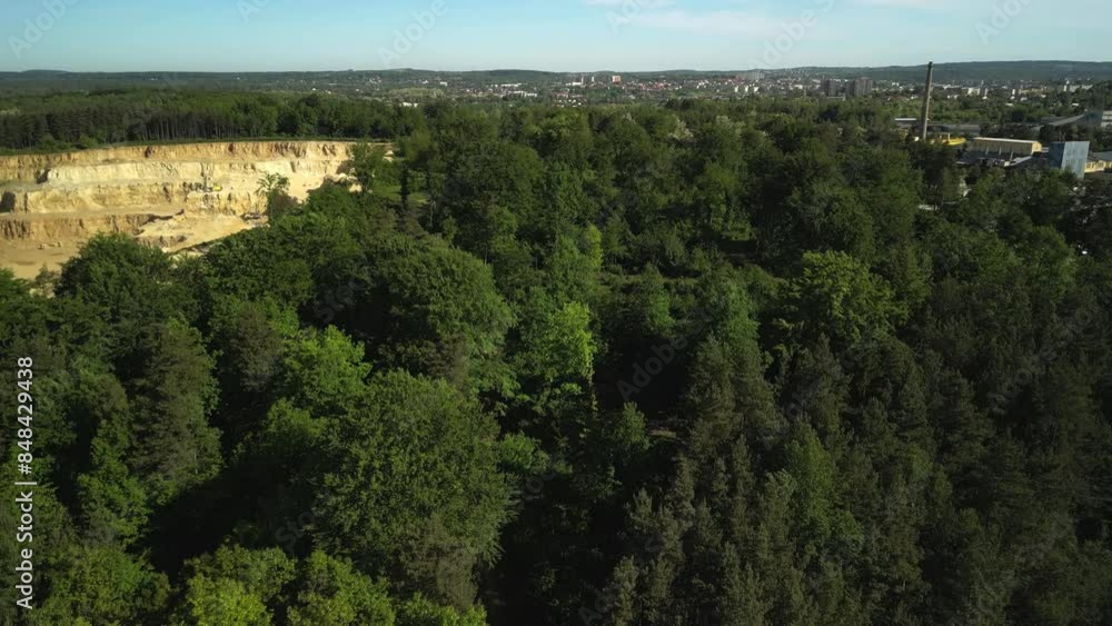 Aerial View of Forest with Open-Pit Dolomite or Limestone Quarry, Blue Sky, and City Background This aerial view from a drone captures a lush forest with a backdrop of an open-pit dolomite or limeston Aerial View of Forest with Open-Pit Dolomite or Limestone Quarry, Blue Sky, and City Background This aerial view from a drone captures a lush forest with a backdrop of an open-pit dolomite or limeston