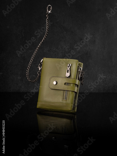 Tan leather wallet with multiple zippered compartments and anti-theft chain decorated with durable stitching, presented on dark reflective surface. Stylish handcrafted accessory